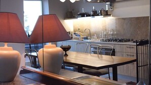 A modern kitchen with a dining area, featuring a wooden table, chairs, and a large vase. - casa Rosa milo (Milo)
