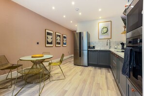 Une cuisine moderne équipée d’un réfrigérateur, d’un four et d’un évier. On y trouve également un coin repas avec une table ronde et des chaises.