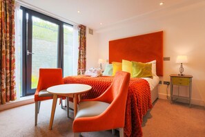 A hotel room with a bed, two chairs, a small table, and a nightstand. - Courtyard Double Room - Penarth Seafront (Vale of Glamorgan)