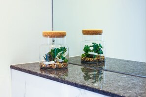 Zwei gläserne Terrarien mit Korkdeckeln auf einer Granitarbeitsplatte.