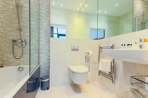 Ein modernes Badezimmer mit einer Duschkabine, einer weißen Toilette und einem Waschbecken mit Handtuchhalter.
