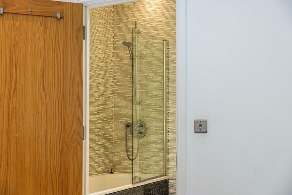 A glass-enclosed shower with a tiled wall, a wooden door, and a marble countertop. - Double Room Courtyard Penarth (Vale of Glamorgan)