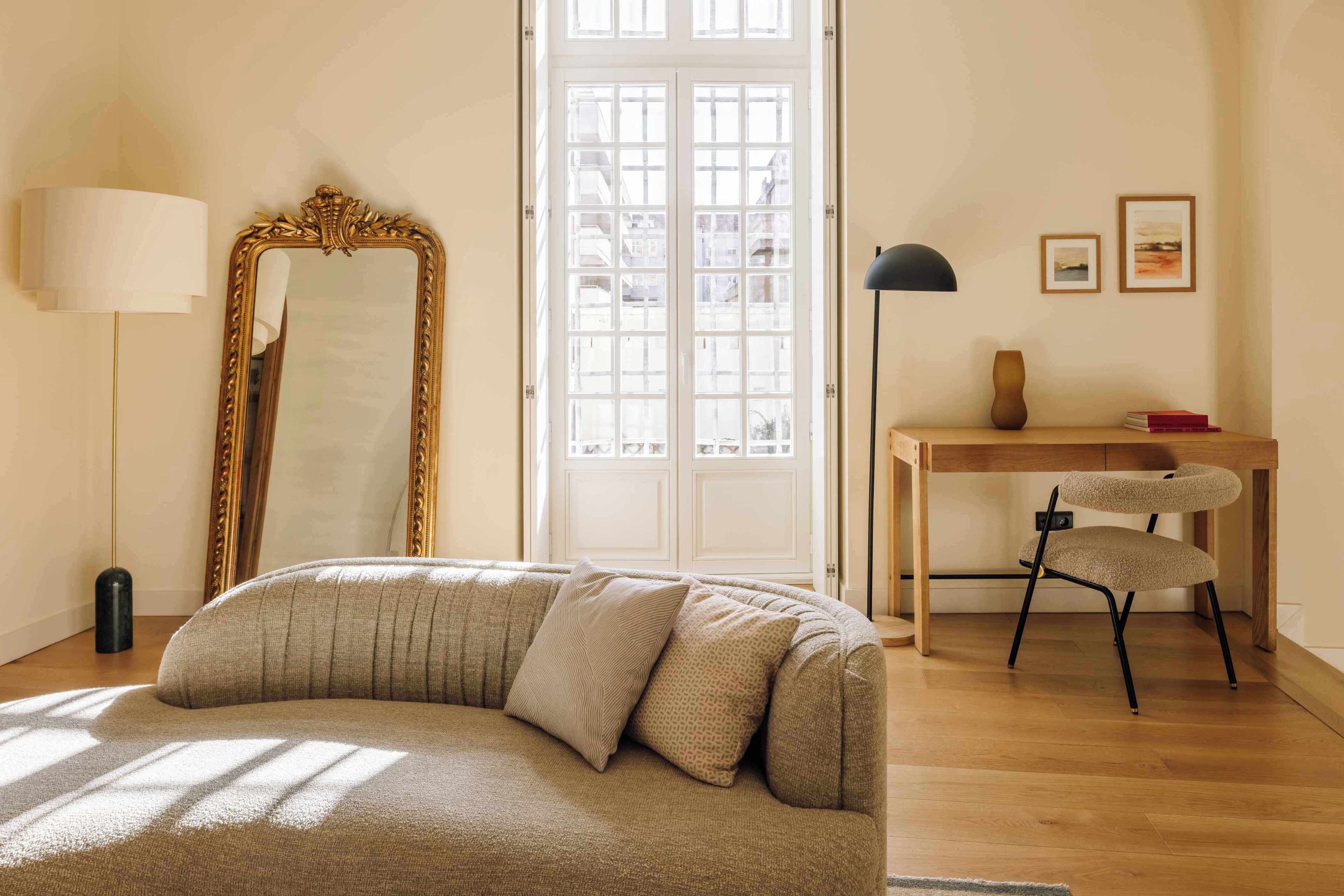 Ein Zimmer mit einer Couch, einem Schreibtisch, einem Stuhl, einem Spiegel und einer Lampe.