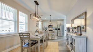 A modern kitchen with white cabinets, a central island, and pendant lighting.