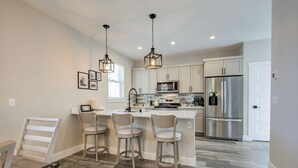 A modern kitchen with white cabinetry, stainless steel appliances, and a central island with bar stools.