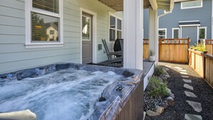 A hot tub in a covered outdoor area with a wooden deck and a stone pathway.