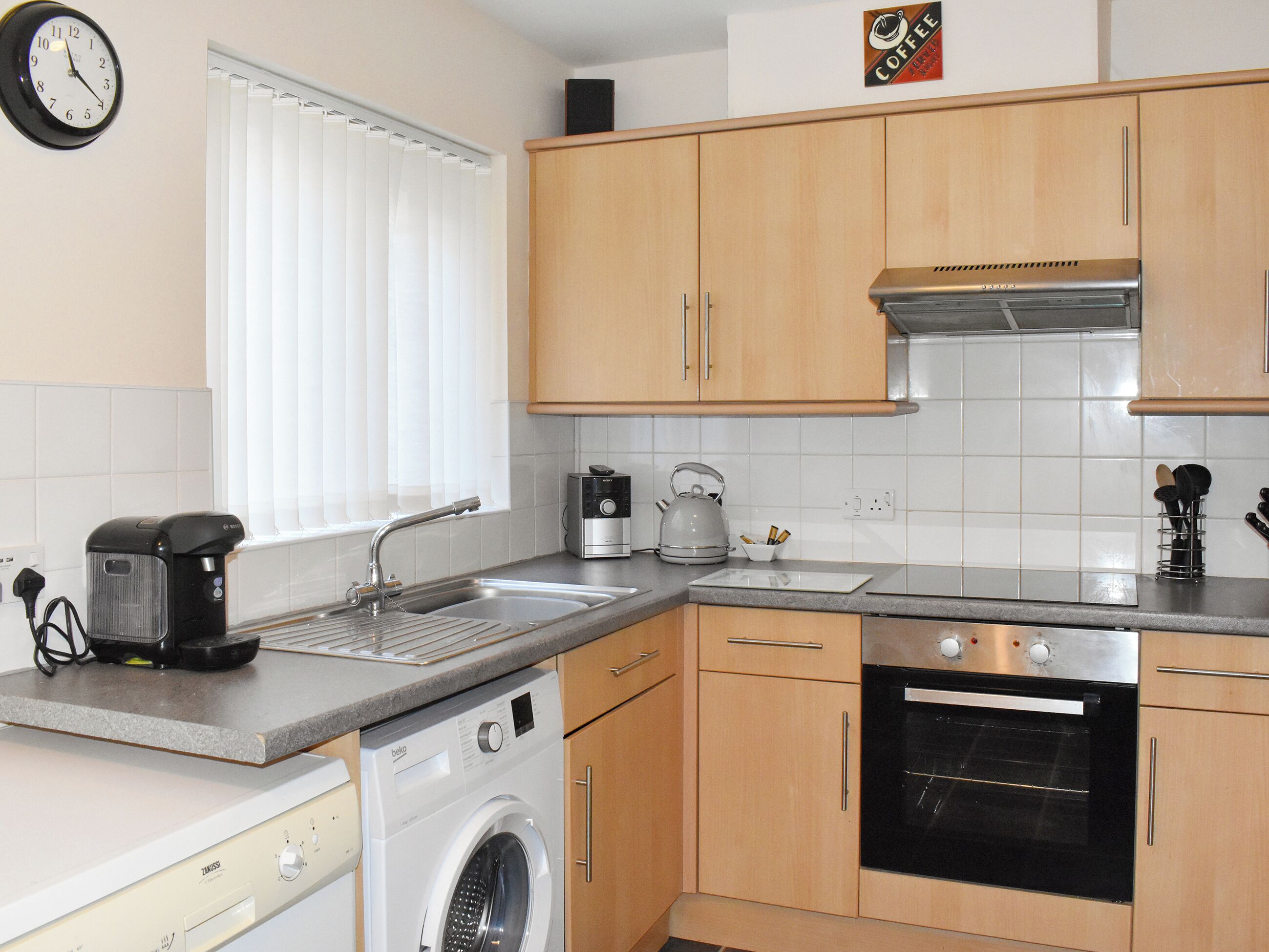 A compact kitchen with a washing machine, a coffee maker, and a toaster.
