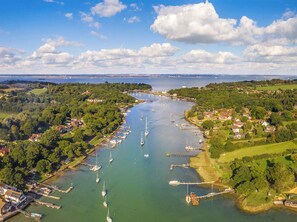 Luchtbeeld van een kustplaatsje met een jachthaven, boten en omliggende begroeiing.