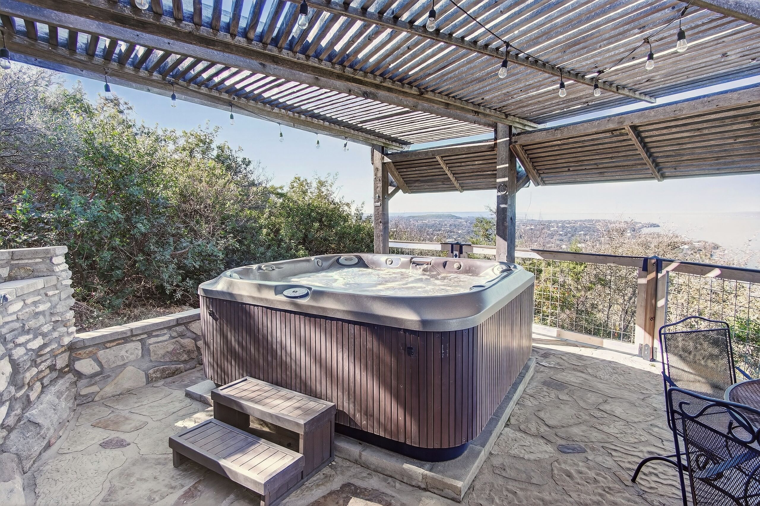 Un bain à remous sous une pergola, avec vue sur la ville.