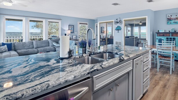 A modern kitchen with a large granite countertop, stainless steel appliances, and a view of the outdoors. - On Top Of SpiderMountain-2Bed/2Bath-HotTub-Gameroom. (Burnet)