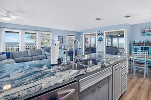 Una cocina moderna con una encimera de granito amplia, electrodomésticos de acero inoxidable y vistas al exterior.