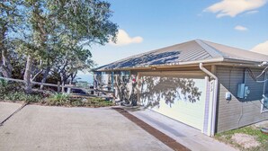 A single-story house with a garage, a covered porch, and a solar panel roof. - On Top Of SpiderMountain-2Bed/2Bath-HotTub-Gameroom. (Burnet)