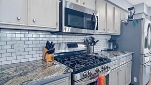 A modern kitchen with white cabinets, a stainless steel microwave, a gas stove, and a refrigerator. - On Top Of SpiderMountain-2Bed/2Bath-HotTub-Gameroom. (Burnet)