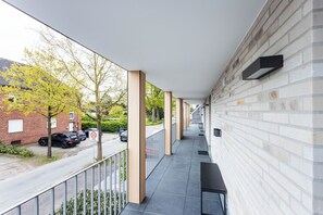 A covered outdoor corridor with a brick wall, a metal railing, and a bench. - City-apparte Boarding -einzel-studios- Grenznähe NL (Gronau (Westfalen))