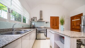 A modern kitchen with granite countertops, stainless steel appliances, and wooden cabinets. - Villa Perla 15 At Playacar phase ll NAS (Playa del Carmen)