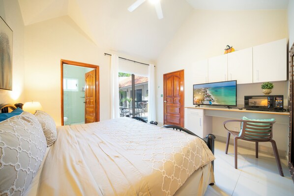 A bedroom with a bed, a desk with a television and a microwave, and a chair. - Villa Perla 15 At Playacar phase ll NAS (Playa del Carmen)