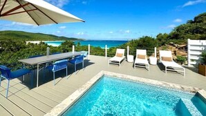 A poolside area with a view of the ocean, a table with chairs, and lounge chairs. - Sea View Villa @ Flamenco Beach, Culebra, Puerto Rico (Flamenco)