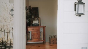Une porte qui mène à une pièce dotée d’un plancher en bois, d’une bibliothèque et d’une lanterne fixée au mur.