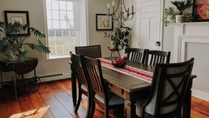 Une salle à manger avec une table en bois, des chaises, un lustre et une fenêtre donnant sur un beau paysage.