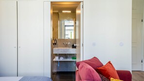 A modern bathroom with a marble sink, a mirror, and a towel rack.