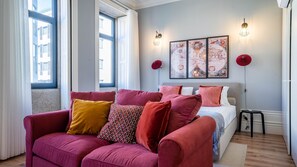 Une chambre moderne avec un canapé rouge, un lit, un globe terrestre fixé au mur et une fenêtre avec des rideaux.