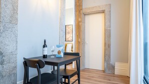 A dining area with a table, chairs, a wine bottle, and a box of snacks. - Sta. Catarina 632 - 2T by LovelyStay (Porto)