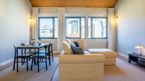 A modern living room with a dining area, large windows with city views, and a cozy seating arrangement. - Sta. Catarina 632 - 3 by LovelyStay (Porto)