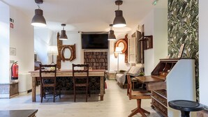Um quarto acolhedor e bem iluminado, com uma mesa de jantar de madeira, cadeiras, uma estante e uma televisão.