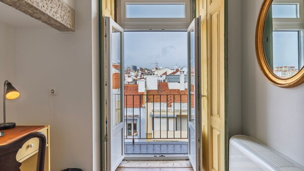 A doorway leading to a balcony with a view of a cityscape.