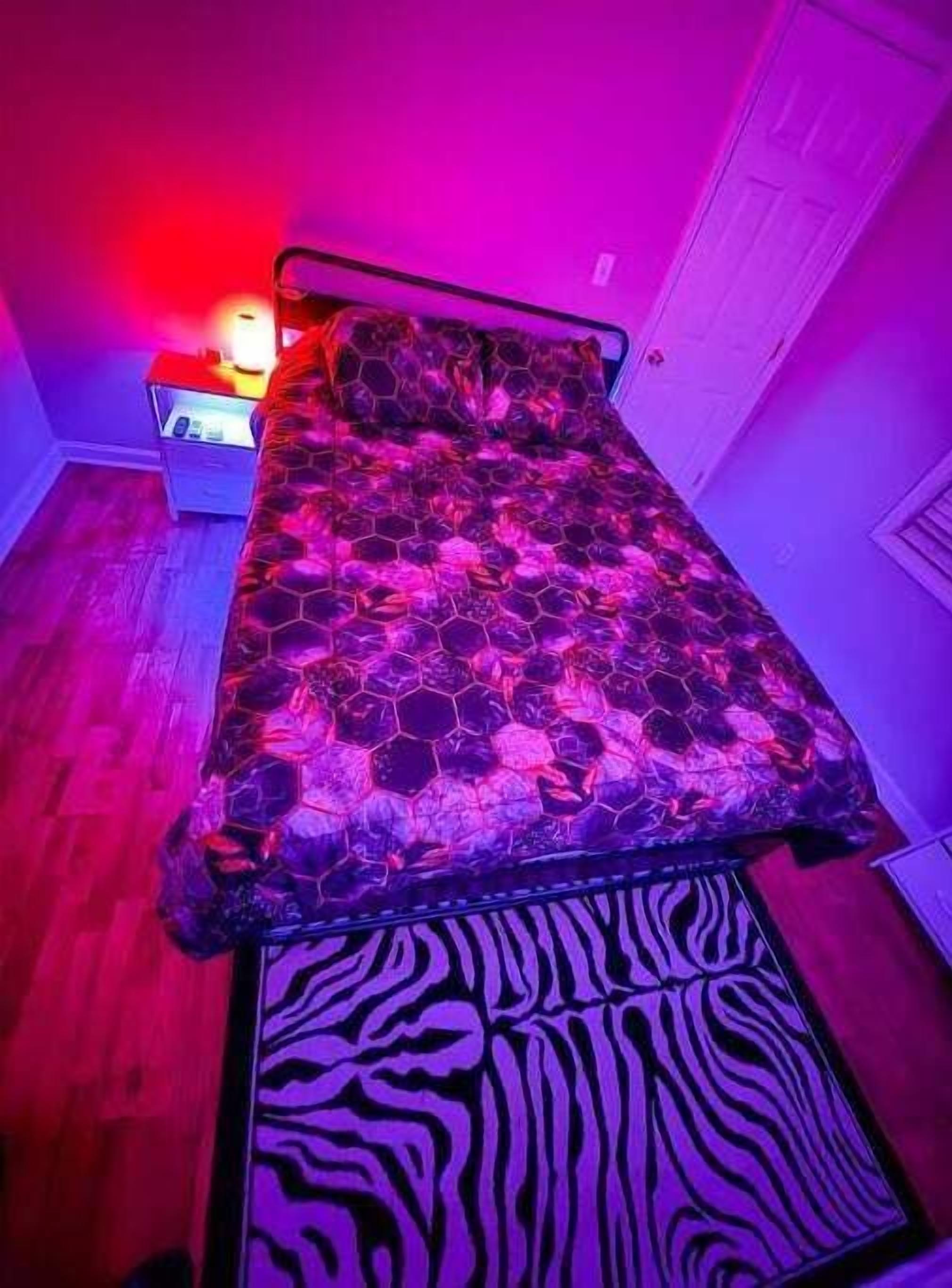 A bedroom with a bed, a nightstand, and a zebra-patterned rug.