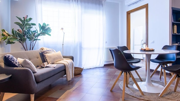 A modern living room with a sofa, dining table, chairs, and a large window with curtains. - Emilia Elegant and Modern Two Steps from Rome (ROMA)