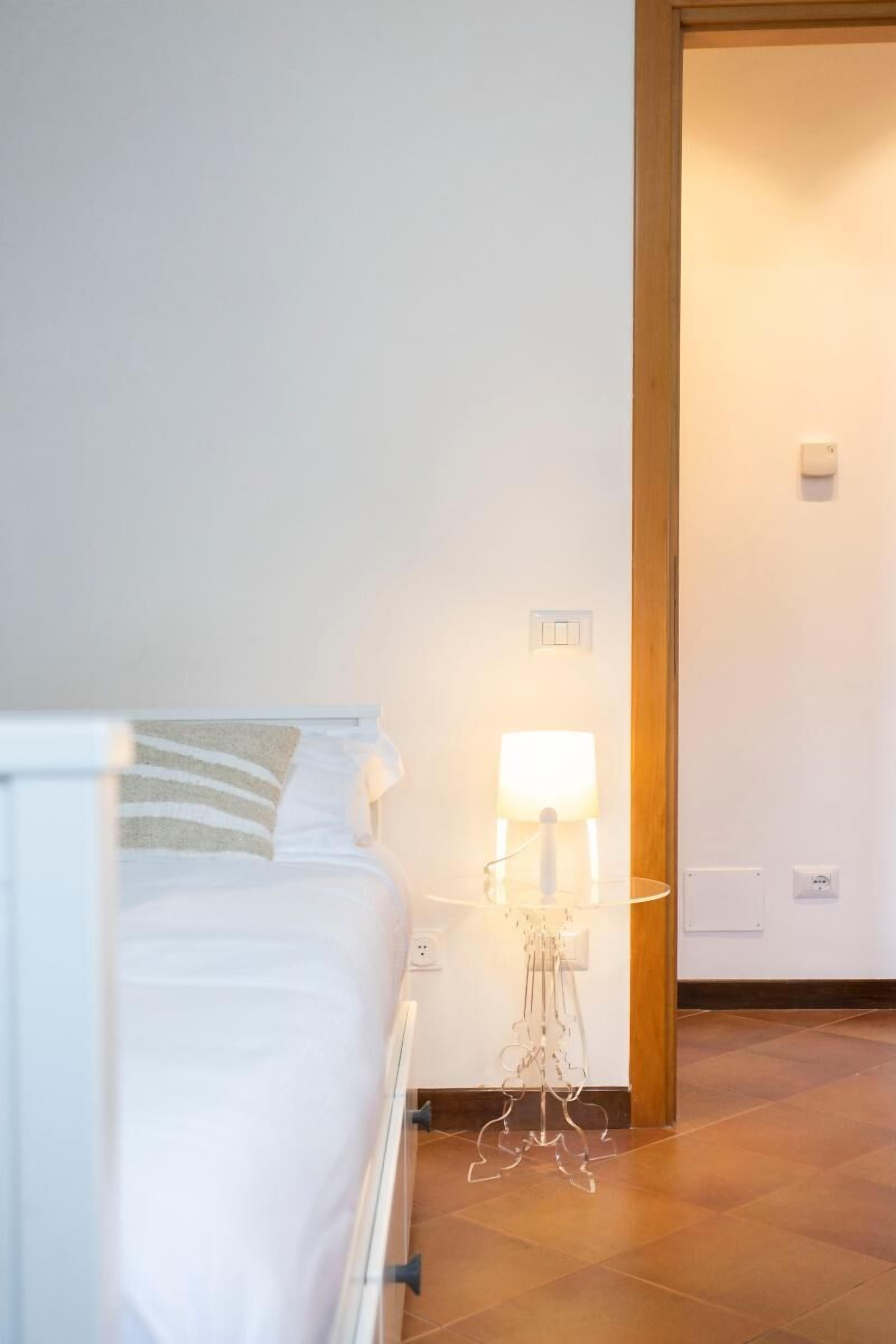 Un dormitorio con cama, mesita de noche con lámpara y puerta de madera.