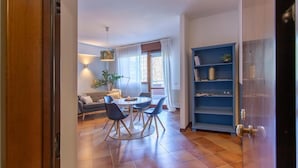 A modern living room with a dining area, a sofa, a coffee table, and a bookshelf. - Emilia Elegant and Modern Two Steps from Rome (ROMA)
