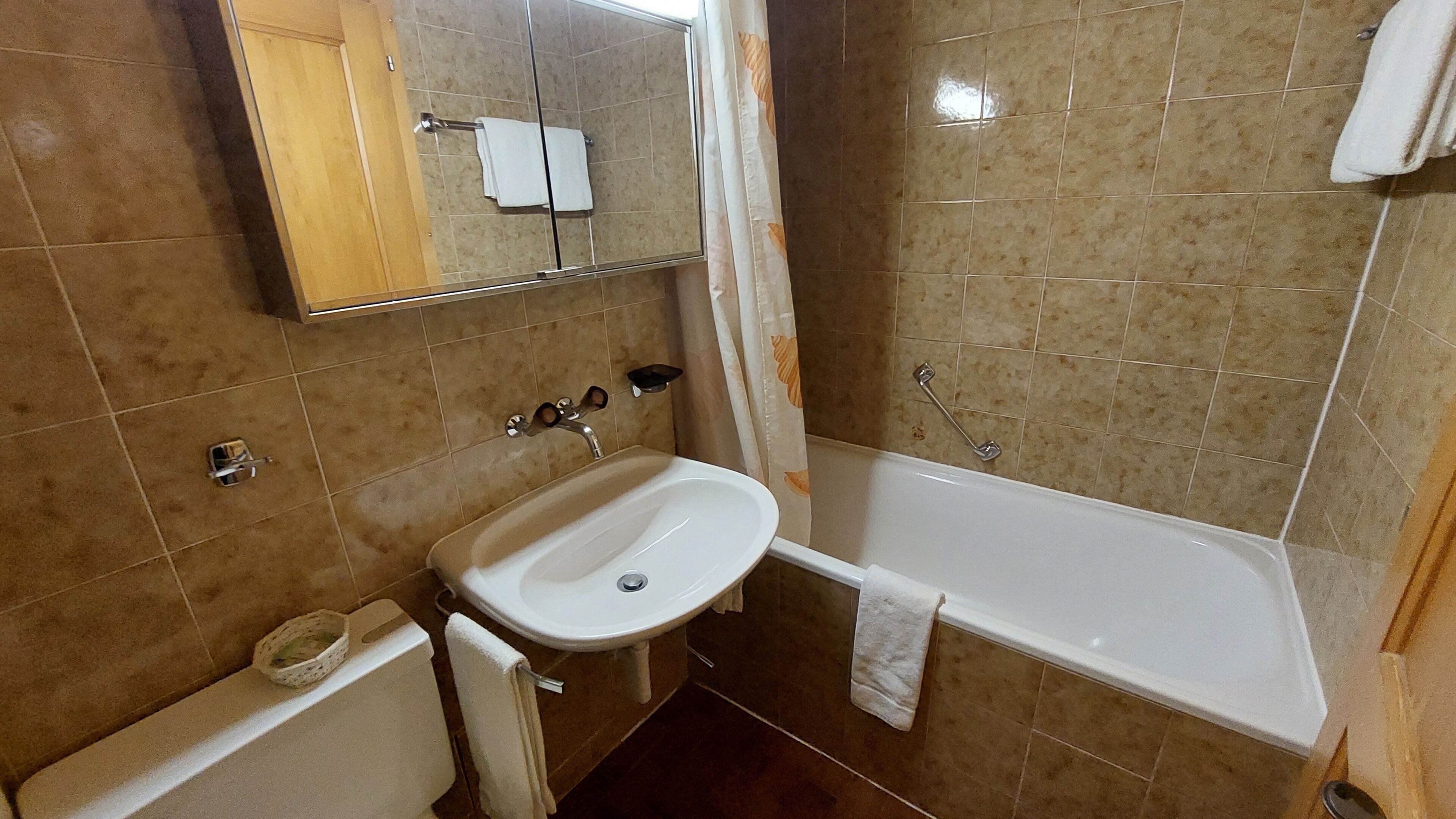 A bathroom with a sink, mirror, and bathtub.