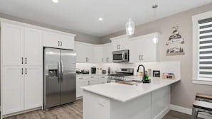 Una cocina moderna con armarios blancos, electrodomésticos de acero inoxidable y una isla central.