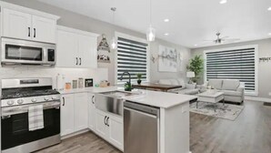 Una cocina moderna con armarios blancos, electrodomésticos de acero inoxidable y una isla central.