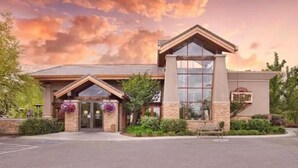 Un hotel con diseño arquitectónico moderno, que presenta una entrada destacada con fachada de vidrio y revestimiento de piedra.