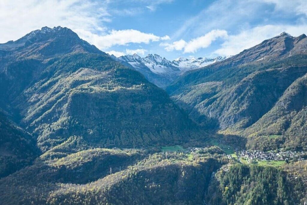 Paisatge montanyós amb una vall i un petit assentament.