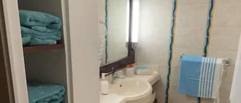 A bathroom with a white sink, a mirror, and a towel rack. There is a blue towel on the floor and a blue towel hanging on the rack.