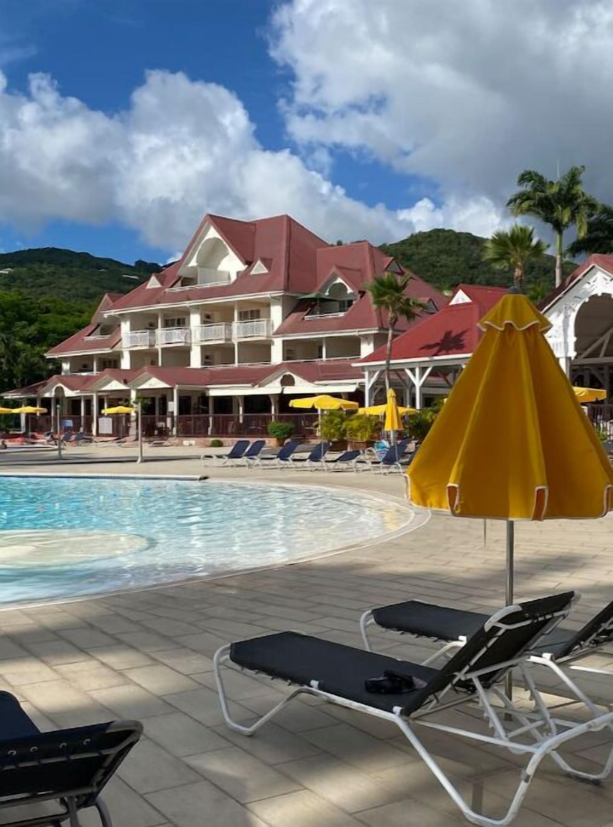A hotel with a pool, lounge chairs, and umbrellas.
