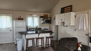 A cozy living room with a dark brown sofa, a small table, and a ceiling fan. - Cozy Cottage with water access, Newly remodeled  (Celina)