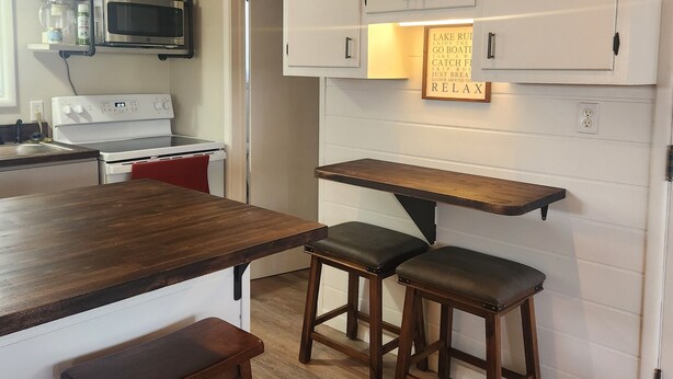 A kitchen with white cabinets, a wooden countertop, and two stools. - Cozy Cottage with water access, Newly remodeled  (Celina)