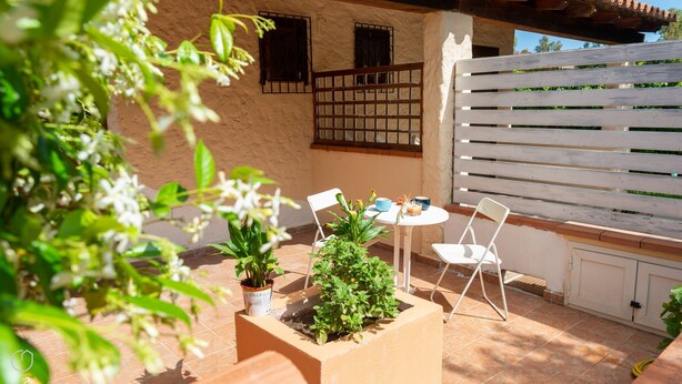 Un patio con una mesa, sillas y plantas en macetas.