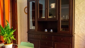 Un área de comedor con un aparador de madera, un reloj en la pared y una planta en maceta.