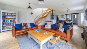 A modern living room with leather sofas, a wooden coffee table, and a staircase leading to an upper level. - Nouelig - A 150m de la plage de la Ria (Plouhinec)