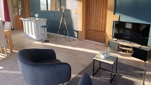 A room with a TV, a tripod, a bar area, and a large chair. - Gîte du Mas Saint Paul - Maison avec piscine (Travaillan)