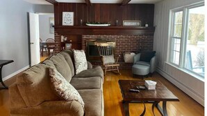 A living room with a brick fireplace, a sofa, a chair, and a coffee table.