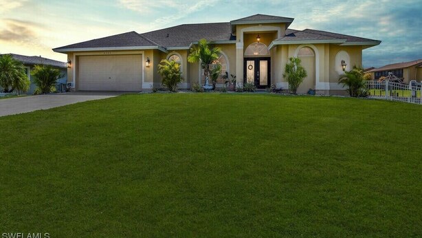 A two-story house with a garage, a well-maintained lawn, and a clear sky.