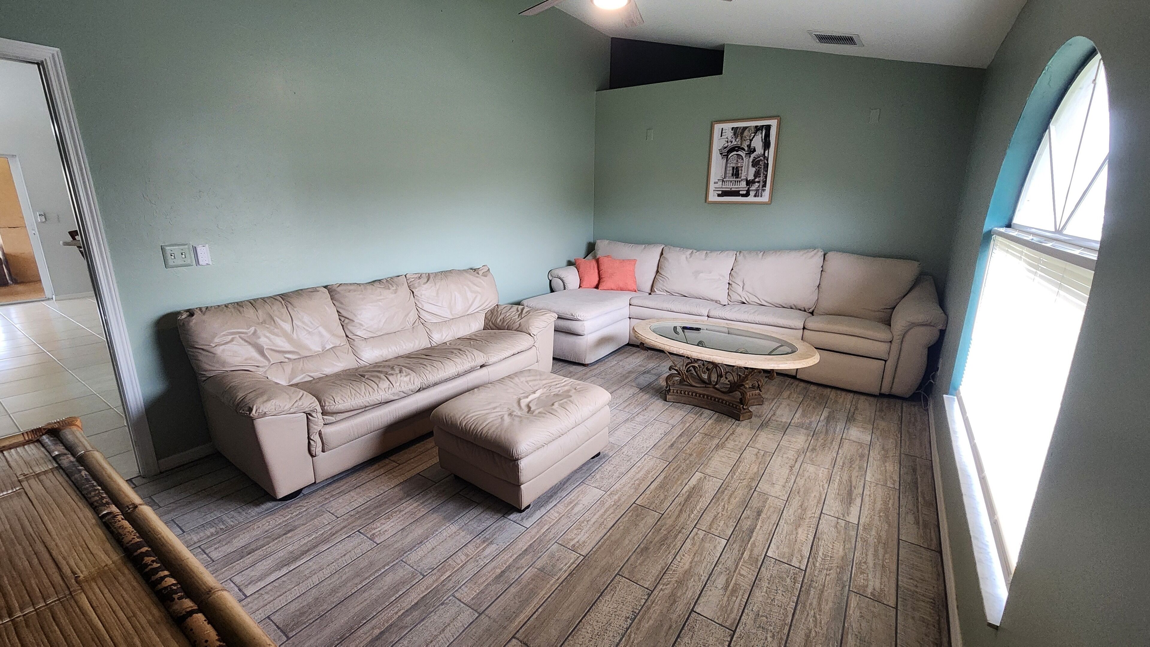 A living room with a sectional sofa, a round coffee table, and a wall-mounted picture.