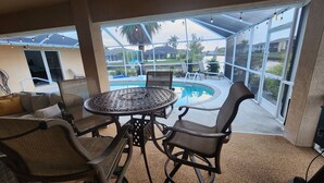 A covered patio area with a pool, outdoor seating, and large windows.